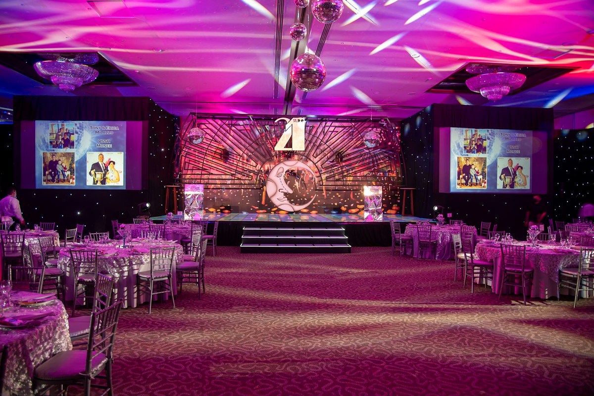 Corporate gala room with a low stage, printed backdrop and dressed round tables
