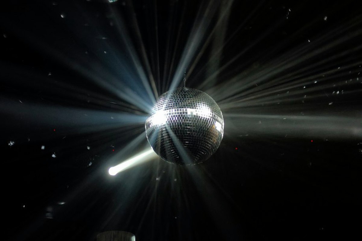 Mirror ball above a busy dance floor with coloured uplighting at a disco night
