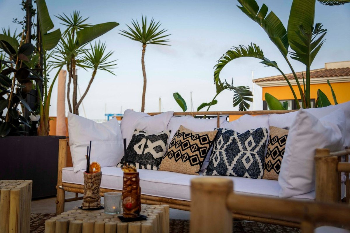 Terrace styled with palms, rattan seating and festoon lighting for a tropical party